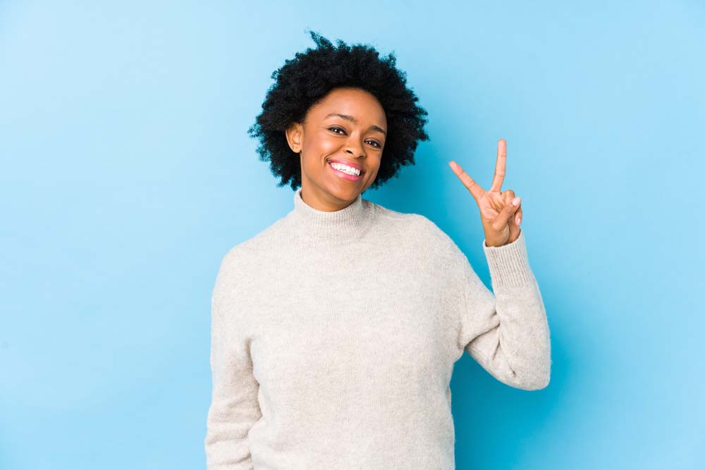 showing victory sign and smiling broadly.